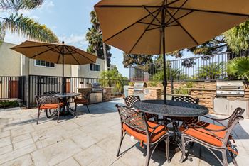 A patio with a table and chairs under umbrellas. at Parkway Plaza Apartments, Culver City, CA